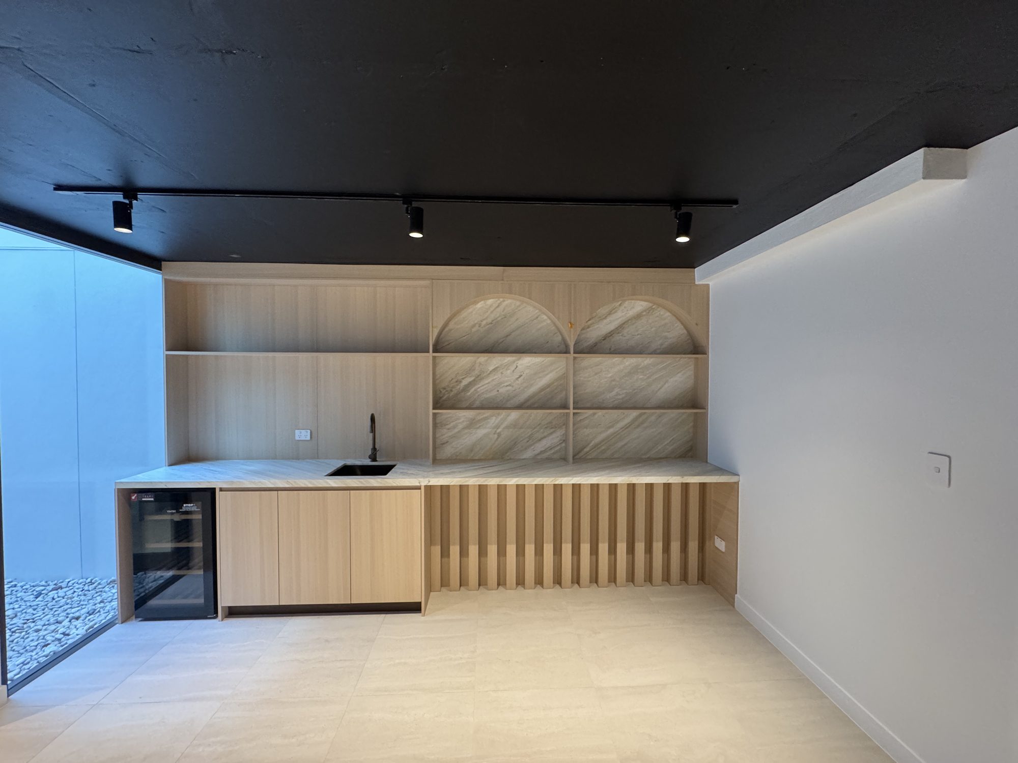 Bar joinery in fluted timber with arched stone niches