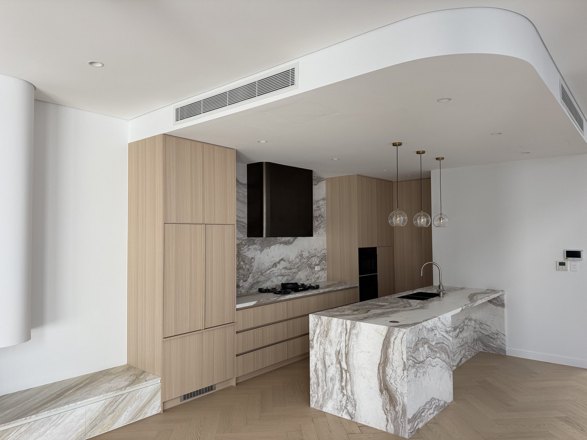 Kitchen with a marble waterfall island and timber joinery on herringbone oak