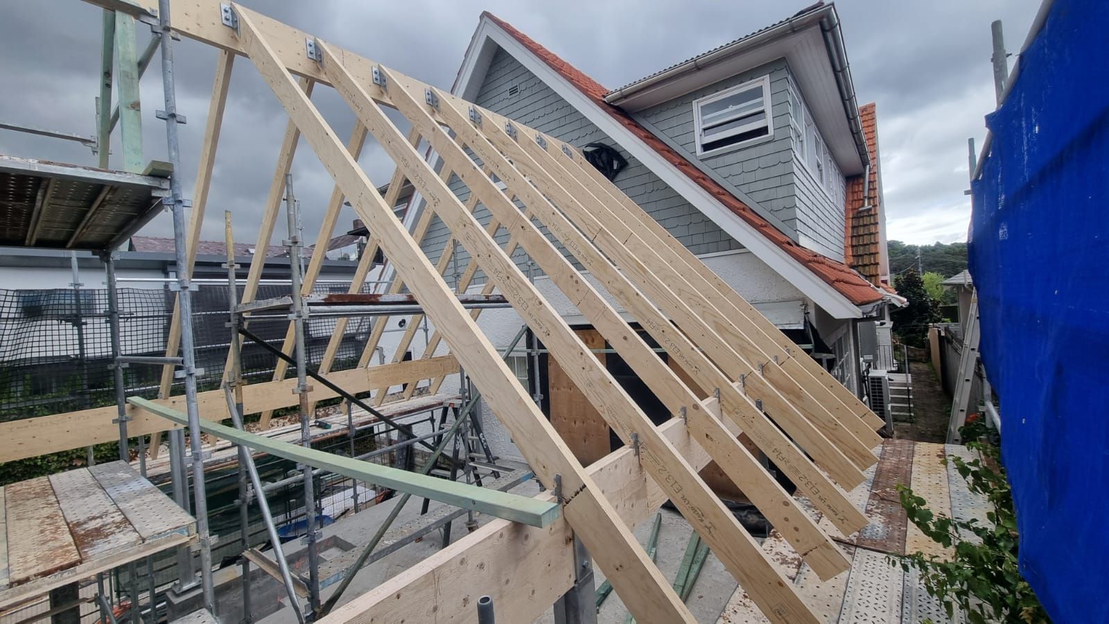 Timber roof framing standing on a scaffolded site.